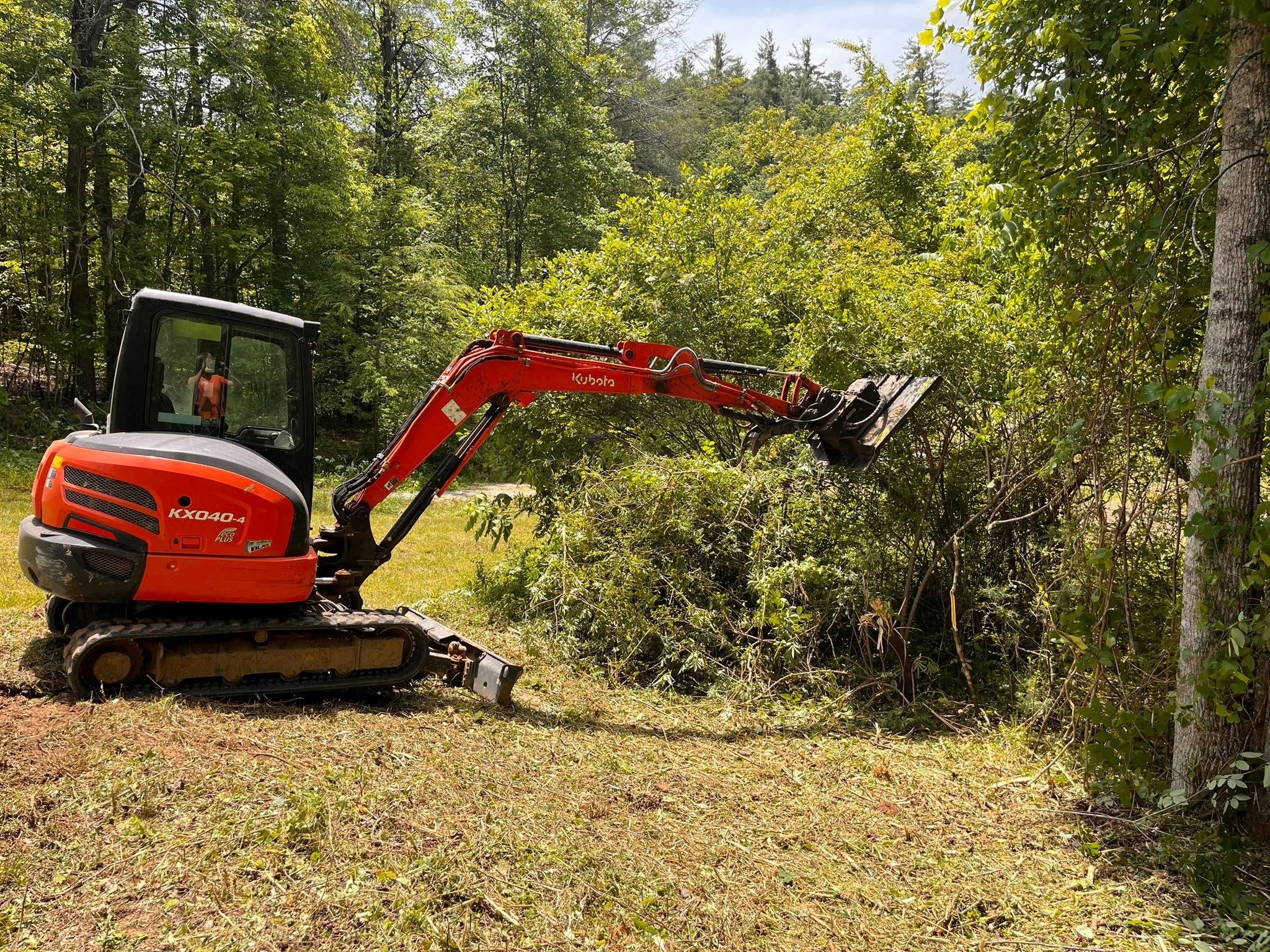 Kubota excavator cutting dense brush with a hydraulic attachment